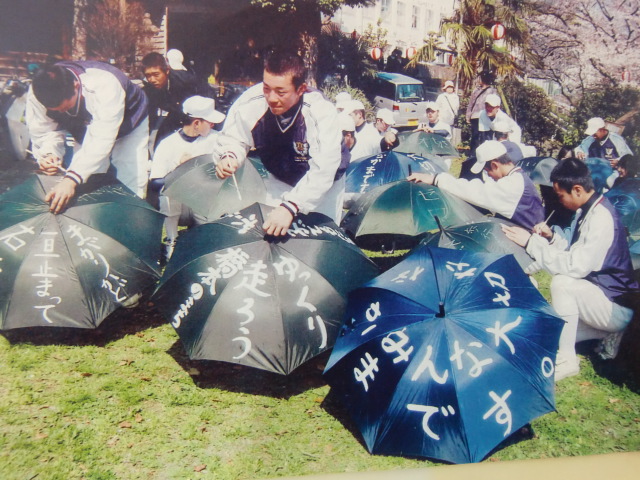 置き傘に啓発標語を書く橋本高校野球部員らの写真
