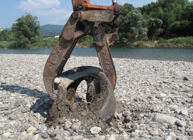 重機で河原から引き上げられる古タイヤ
