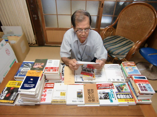 戦争関係の寄贈本６６冊と匿名の手紙に感銘する阪口さん（自宅で）