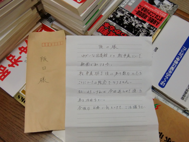 戦争関係の寄贈本６６冊と匿名の手紙に感銘する阪口さん（自宅で）