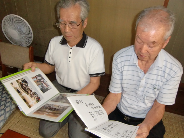 同窓生の過去帳を見る巽さん（右）とアルバムを見る土生さん