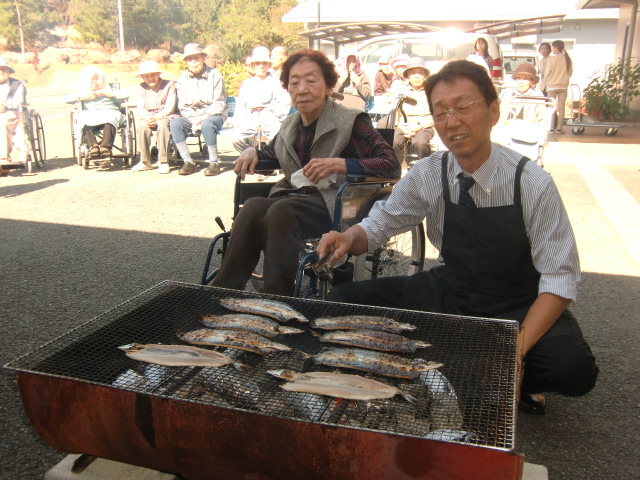 施設のお年寄りの前で秋刀魚などを炭火焼きする南陽食品の木村専務